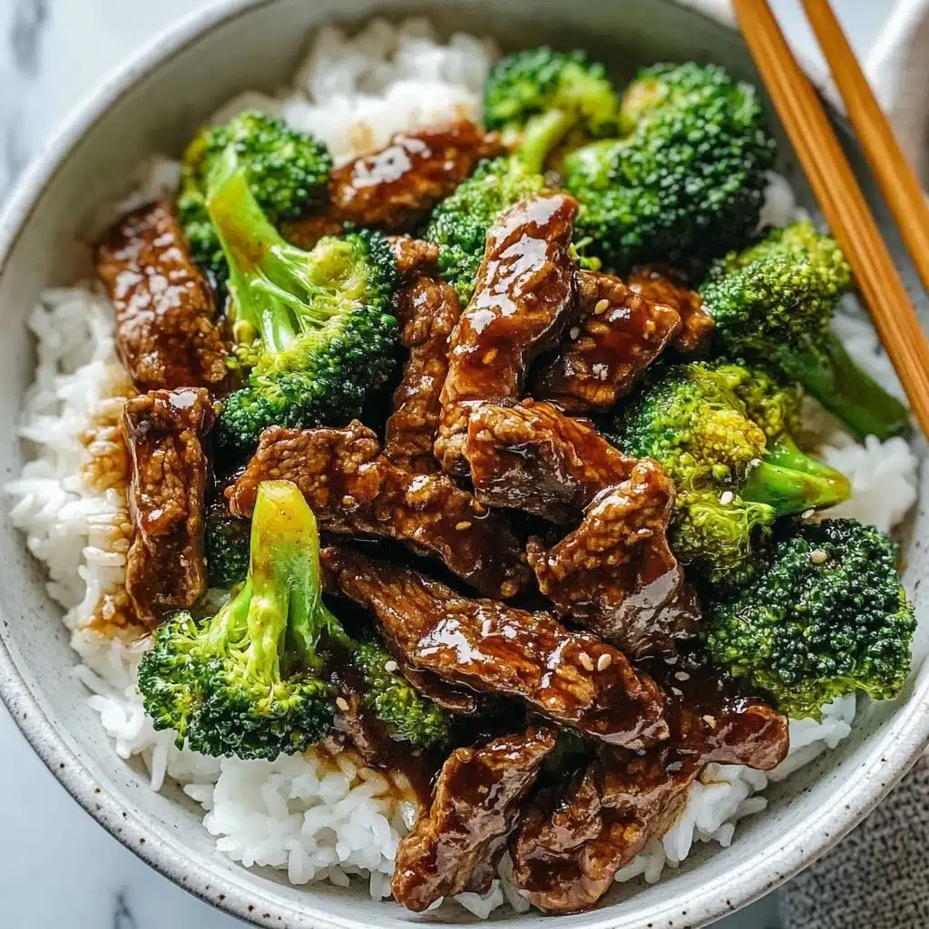 Chinese Beef and Broccoli, Chinese Beef and Broccoli stir-fry, easy Chinese beef recipes, healthy beef stir-fry, quick weeknight dinner recipes A white bowl filled with a base layer of fluffy white rice, topped with a layer of glossy, dark brown beef strips mixed with bright green broccoli florets. The beef has a shiny, saucy texture and the broccoli looks fresh and slightly cooked, contrasting nicely with the rice below. The bowl is set on a white marbled surface, with a pair of wooden chopsticks resting on the edge.
