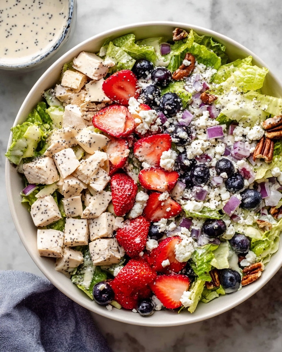 A white bowl filled with a vibrant salad placed on a white marbled surface. The bottom layer is green lettuce leaves spread evenly. On top, there are small cubes of white cooked chicken scattered around. Bright red strawberry halves and whole dark blueberries are arranged in clusters across the salad. Finely chopped purple onions are sprinkled throughout, adding small pops of color. Crumbled white cheese and crunchy pecan pieces are spread over the top, with a light drizzle of creamy dressing giving a shiny texture on the strawberries and cheese. The scene includes a slightly blurred white and red striped cloth in the background. Photo taken with an iphone --ar 4:5 --v 7