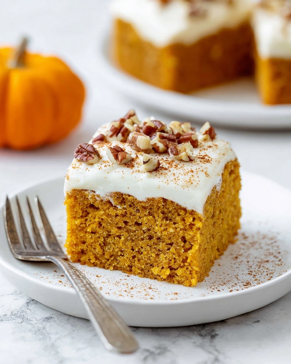 A square piece of moist, orange-brown pumpkin cake with a soft, porous texture sits on a white plate with a white marbled background. The cake is topped with a thick, smooth layer of creamy white frosting sprinkled with small pieces of chopped pecans and a light dusting of cinnamon. A fork holds a small slice lifted slightly from the cake, showing the contrast between the golden cake and the white frosting. The scene is bright and close-up, capturing the details of the cake and toppings clearly. photo taken with an iphone --ar 4:5 --v 7
