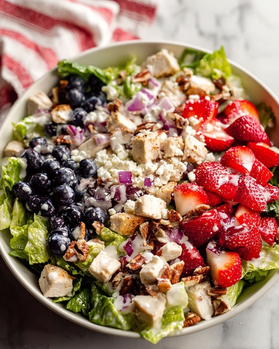A white bowl sits on a white marbled surface filled with a colorful salad made of four main layers. The base layer is fresh green lettuce leaves, roughly cut and arranged all around the bowl. On top of the lettuce is a layer of small cubed white tofu scattered unevenly on two opposite sides. Next, there is a mix of dark blue blueberries and bright red sliced strawberries spread mainly over the center area. Small bits of light purple chopped red onion and brown chopped nuts are sprinkled all over the salad. The top layer is a light dressing drizzled over the entire dish, adding a glossy texture. In the corner of the image, a portion of a white bowl containing more dressing is visible. Photo taken with an iphone --ar 4:5 --v 7