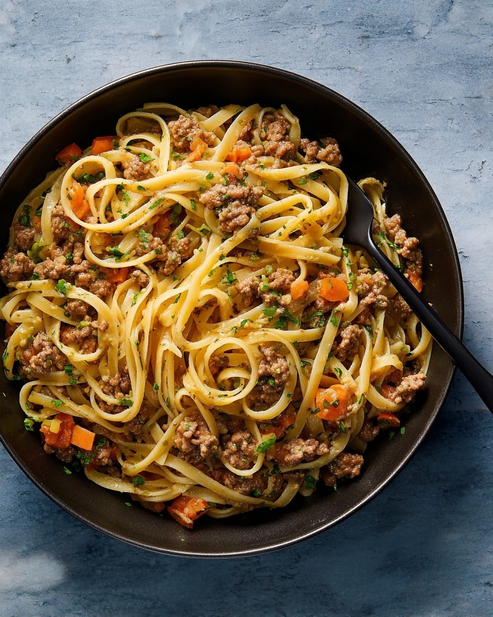 This image shows a black bowl filled with pasta noodles mixed with ground meat, small pieces of orange carrot, and chopped green herbs. The long pasta noodles are creamy light brown and twisted around a black fork inside the bowl. The ground meat is brown and spread evenly through the pasta. The background surface is a white marbled texture. photo taken with an iphone --ar 4:5 --v 7