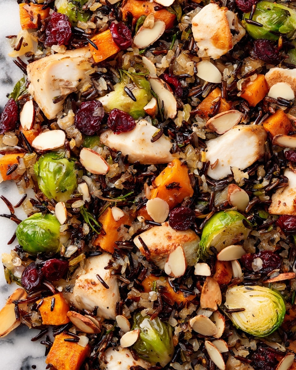 This close-up image shows a mixed dish with several layers and colors. The base is mostly made of cooked wild rice with brown and black grains scattered throughout. On top of the rice are large chunks of white, lightly browned cooked chicken pieces. Bright green Brussels sprouts, some halved, are mixed with orange sweet potato cubes. Red dried cranberries are spread on top, adding pops of color. Thin, light tan almond slices are scattered all over, giving texture and contrast. The food is presented on a white marbled surface, photo taken with an iphone --ar 4:5 --v 7