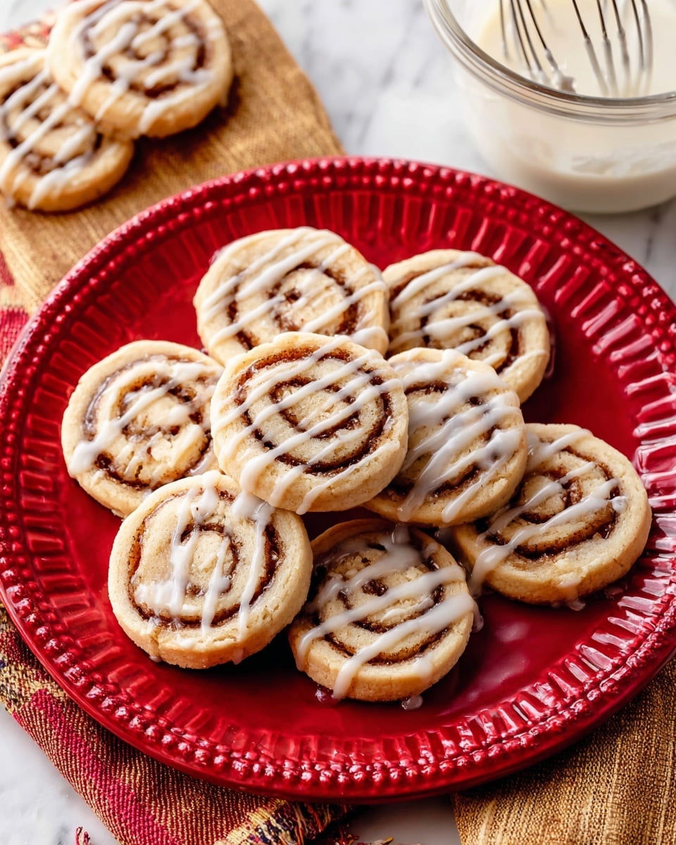 The image shows a group of small round cinnamon rolls placed on parchment paper on a white marbled surface. Each roll has visible layers with an inner spiral of dark brown cinnamon filling and a light golden-brown dough on the outside. The cinnamon rolls are drizzled with white icing in uneven horizontal lines across the top, creating a glossy texture that contrasts with the soft baked surface of the rolls. The rolls are laid out closely, filling the frame evenly. Photo taken with an iphone --ar 4:5 --v 7
