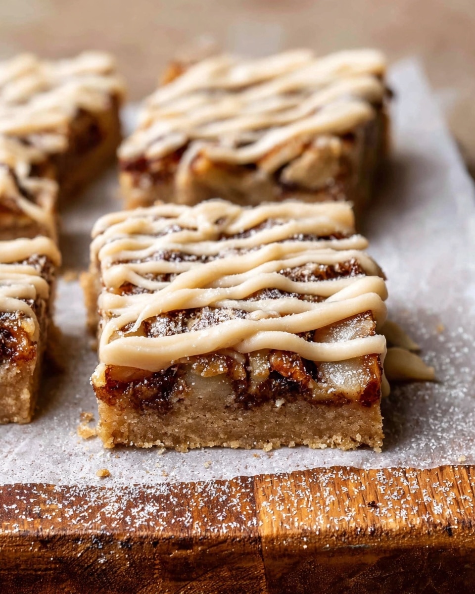 The image shows a square piece of dessert bar with three visible layers. The base layer is a light brown, slightly crumbly crust. The middle layer is darker brown and chunky, with pieces possibly of nuts or fruit inside, giving it a rough texture. The top layer is a light beige drizzle, thick and creamy, spread in thin lines across the bar. The bar sits on a piece of parchment paper, which rests on a wooden surface replaced with a white marbled texture. A sprinkle of fine light powder, possibly cinnamon or sugar, dusts the top. The edges and top of the dessert look moist and soft. Photo taken with an iphone --ar 4:5 --v 7