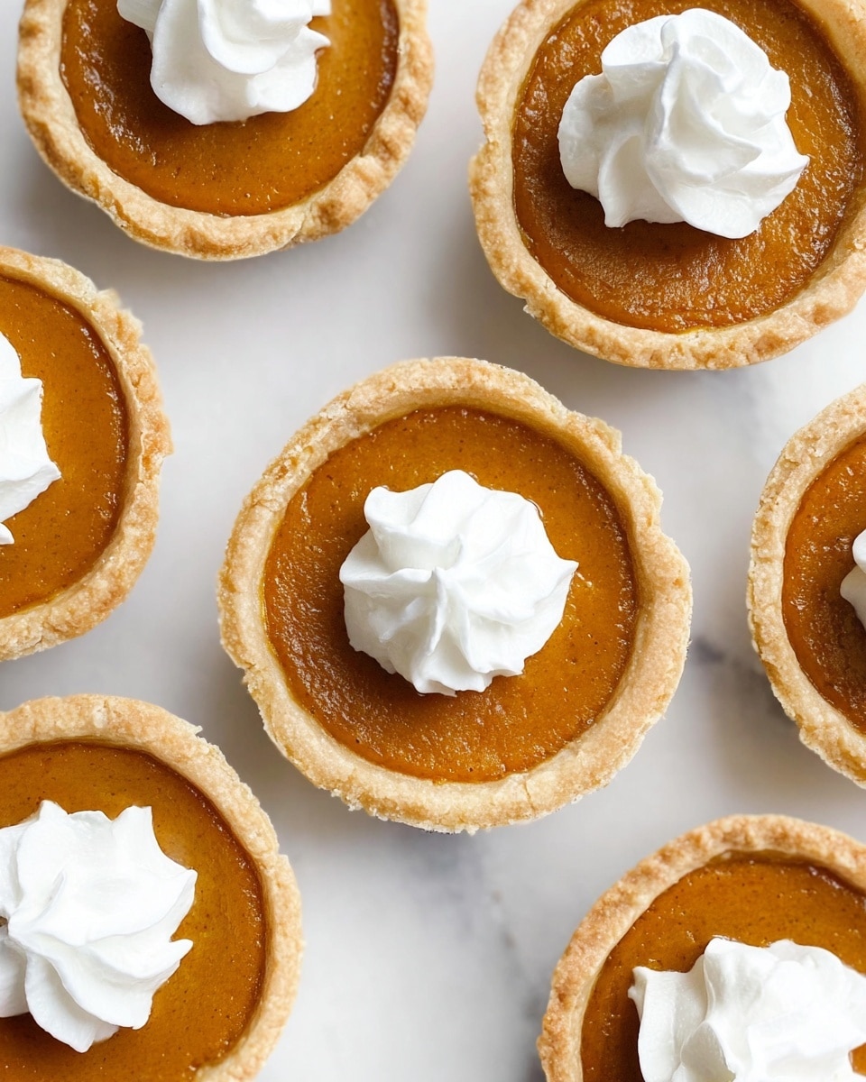 The image shows several small pies arranged on a white marbled surface. Each pie has one layer of golden brown filling with a smooth, slightly shiny texture, held inside a light beige crust that is firm and crumbly. On top of each pie is a small swirl of white whipped cream, thick and soft in appearance, placed right in the center. The pies are spaced evenly, showing off the clean edges of the crust and the creamy topping that adds a bright contrast to the warm color of the filling. photo taken with an iphone --ar 4:5 --v 7