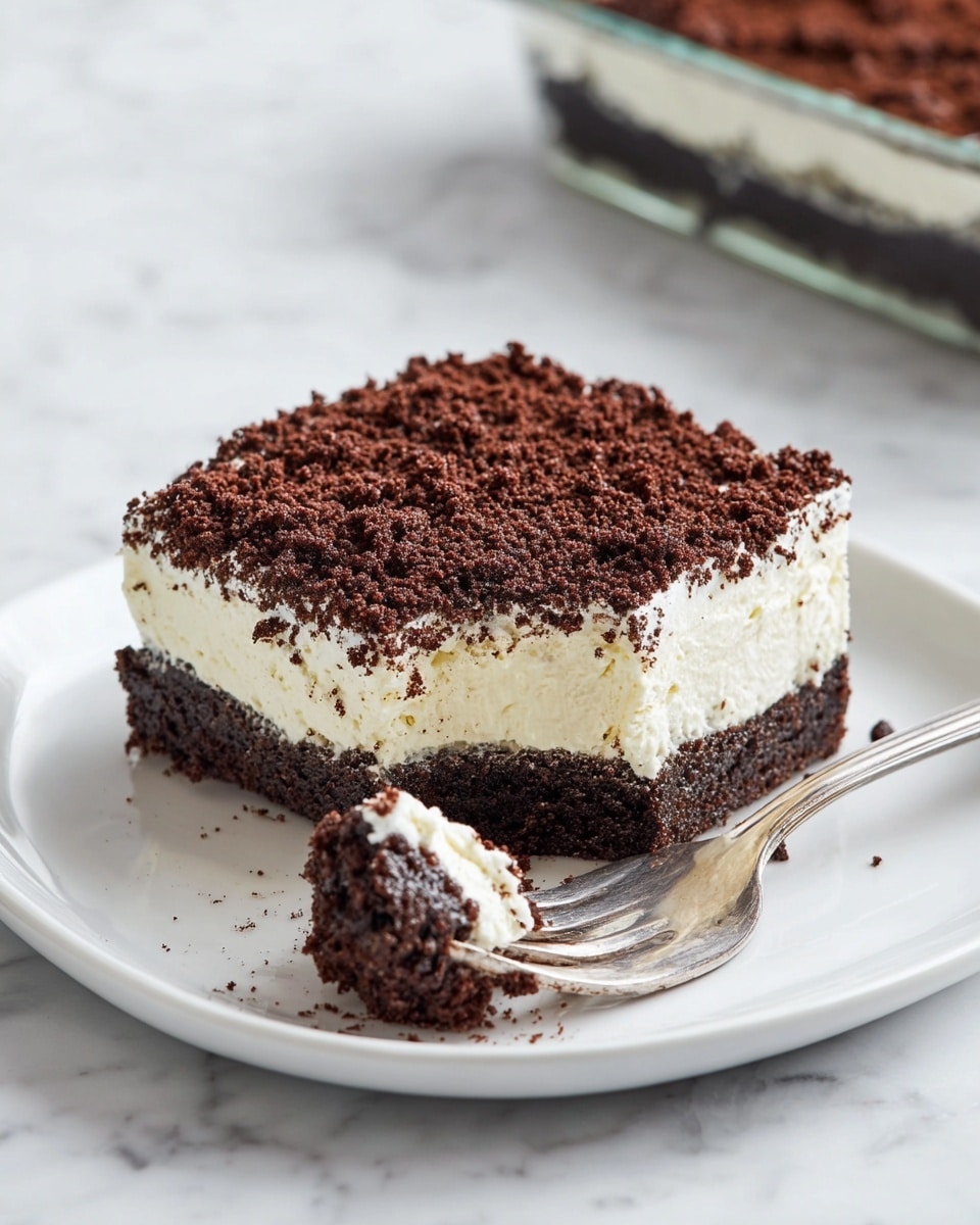 The image shows a square glass dish with three visible layers of dessert: the bottom layer is a dark crumbly chocolate base, the middle layer is a thick, creamy pale yellow filling, and the top layer is a thick, dark chocolate crumb topping that looks coarse and crumbly. A section of the dessert is missing from the front right corner, revealing the clean cut edges and textures of each layer. The dish is placed on a white marbled surface with a blurred jar and a striped cloth in the background. photo taken with an iphone --ar 4:5 --v 7