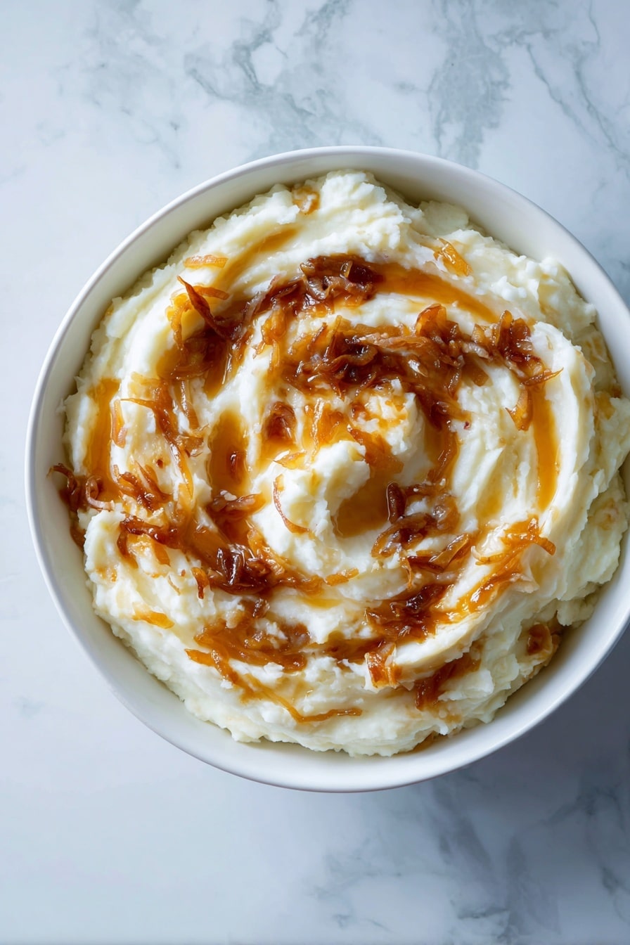 A white bowl filled with creamy mashed potatoes forms the base layer, with a smooth, thick texture. Swirled on top are golden brown caramelized onions, scattered unevenly in rich, glossy patches that follow the curves of the mashed potatoes, adding contrast with their shiny, slightly crispy look. The bowl sits on a white marbled surface, lending a clean and bright background to the warm, comforting dish. photo taken with an iphone --ar 2:3 --v 7 - French Onion Mashed Potatoes, caramelized onion mashed potatoes, creamy onion mashed potatoes, gourmet mashed potato sides, cheesy onion mashed potatoes