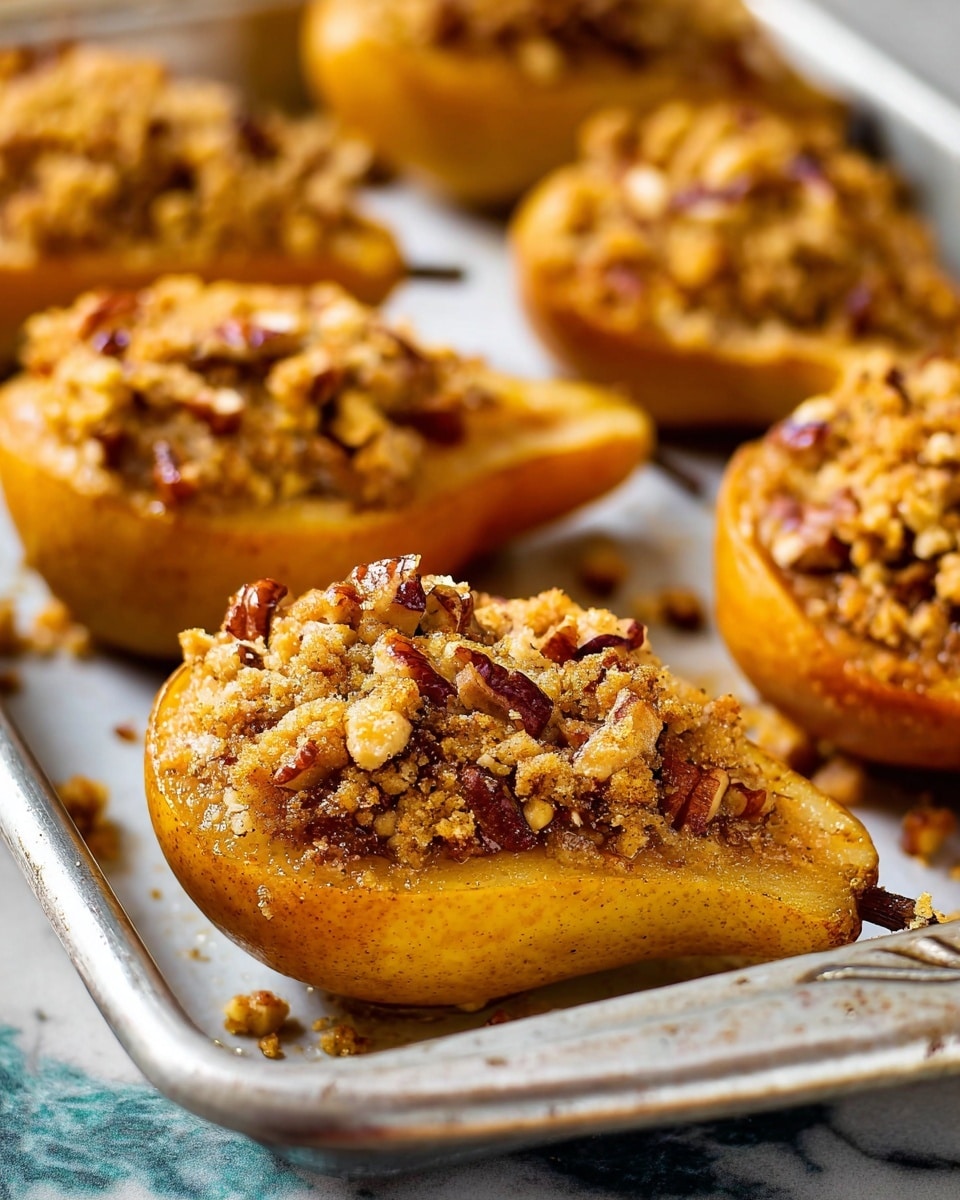 The image shows a close-up of several baked pear halves placed on a silver baking tray with a white marbled surface underneath, each half filled with a crumbly topping that is light brown and textured with small pieces of chopped nuts, likely pecans, scattered on top. The pears have a soft golden-brown edge and a slightly wrinkled surface around the filling, indicating they are cooked. The filling looks crumbly and rough, sitting well above the pear surface, and the nuts add a cracked, crunchy texture. The background shows more of these stuffed pears out of focus. Photo taken with an iphone --ar 4:5 --v 7