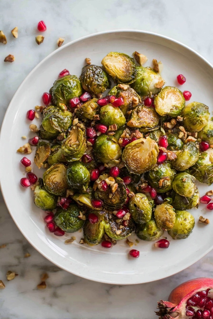A white plate is filled with roasted Brussels sprouts that are halved, showing golden-brown edges and green insides, mixed with bright red pomegranate seeds scattered evenly throughout. Small pieces of chopped nuts are sprinkled on top, adding a crunchy texture with light brown shades. The plate sits on a white marbled surface, and a half-open pomegranate with its red seeds visible is placed to the side of the plate. The image has natural lighting, highlighting the shiny and crispy texture of the Brussels sprouts and the glossy seeds. Photo taken with an iphone --ar 2:3 --v 7 - Roasted Maple Mustard Brussels Sprouts with Pistachios and Pomegranate, Brussels sprouts with maple mustard, festive veggie side dish, healthy holiday Brussels sprouts, easy roasted Brussels sprouts
