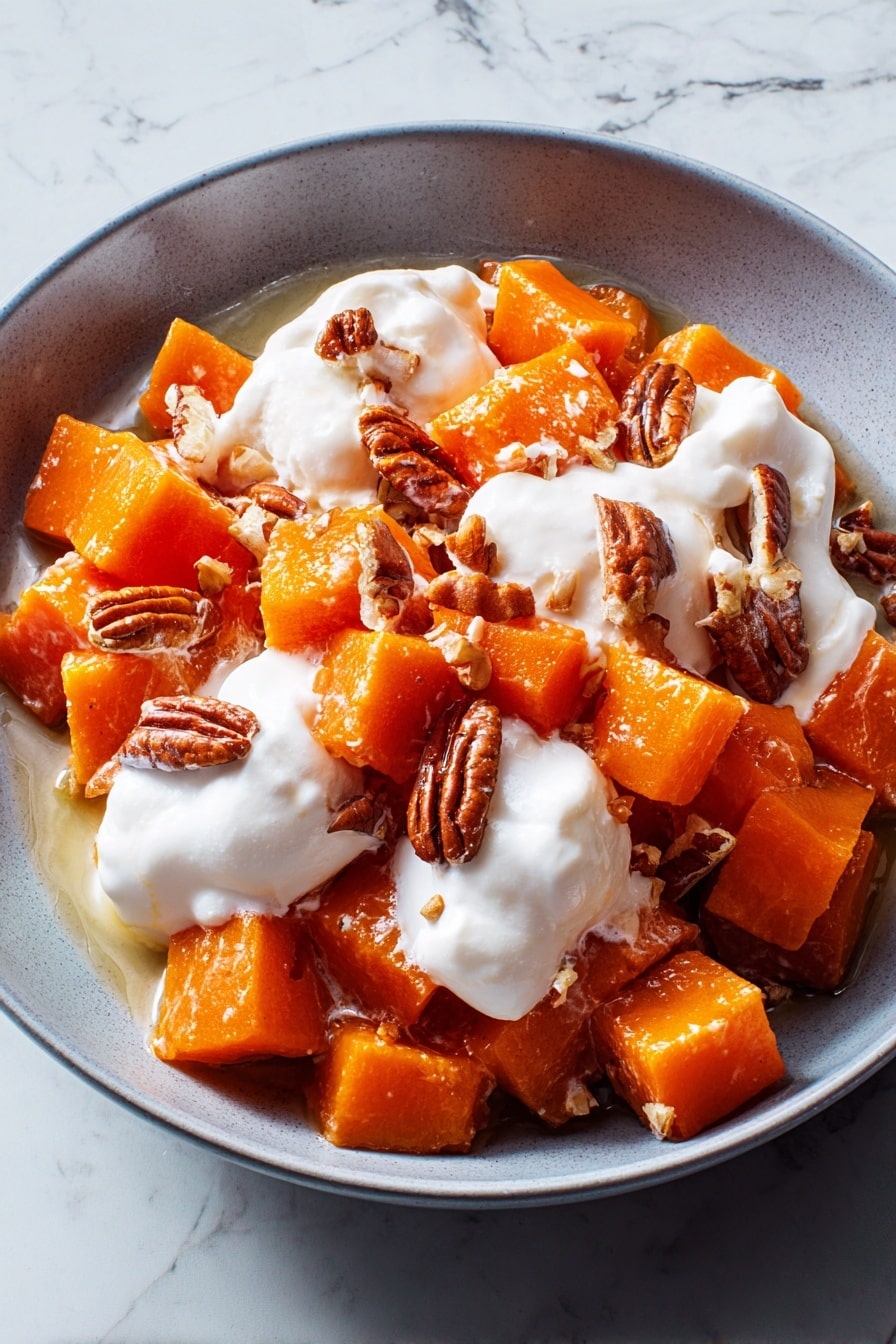 The dish shows a close-up of a casserole filled with soft orange sweet potato cubes layered with small, white marshmallows and topped with whole brown pecan nuts. The marshmallows are melted and slightly foamy, spread unevenly across the dish, mingling with the sweet potatoes that look tender and glossy. The pecans sit scattered on top, adding a crunchy texture. There is a silver spoon scooping the mixture, with a woman's hand holding it gently. The background features a white marbled texture. Photo taken with an iphone --ar 2:3 --v 7 - Crockpot Sweet Potato Casserole with Marshmallows and Pecans, sweet potato casserole, slow cooker sweet potato side dish, marshmallow pecan sweet potato, holiday sweet potato casserole