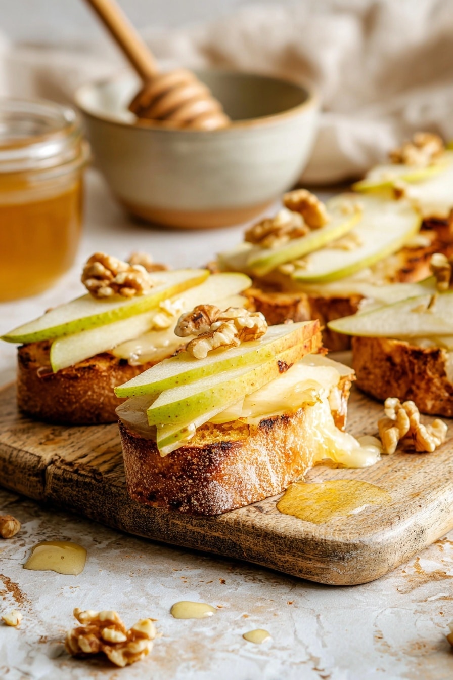 Several pieces of toasted bread sit on a wooden board with a golden cheese crisp around each slice. Each piece has two thin pale yellow pear slices layered on top, followed by small uneven clusters of light brown walnuts. A wooden honey dipper drizzles golden honey over one piece, creating shiny drops and a sticky texture on the toppings. The background is a white marbled texture. photo taken with an iphone --ar 2:3 --v 7 - Parmesan Crusted Crostini with Pear, Walnuts & Hot Honey, pear crostini appetizer, savory sweet crostini, easy elegant appetizer, crunchy cheese crostini