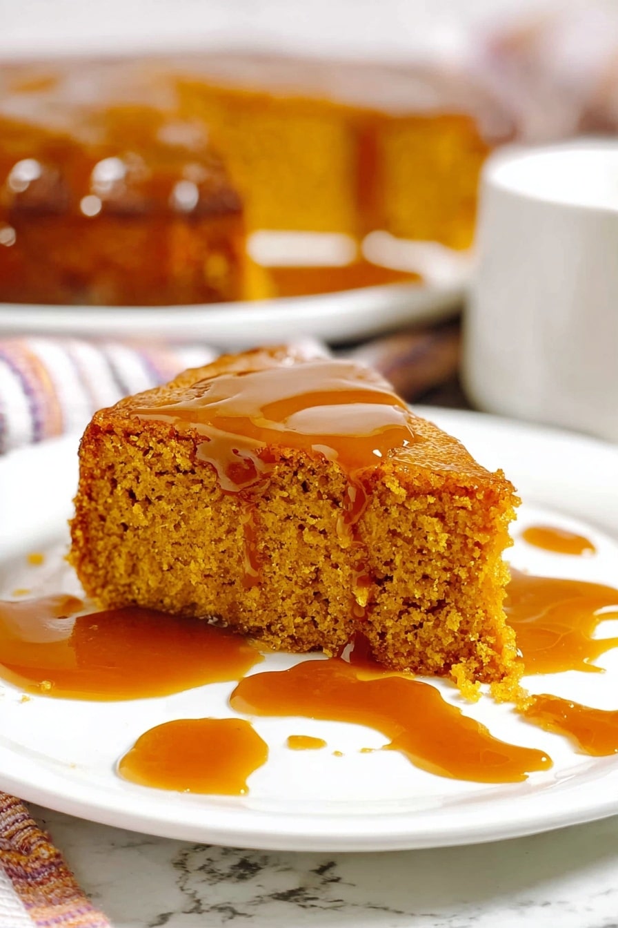 A close-up of a single slice of orange pumpkin cake with a thick, shiny caramel sauce dripping down its spongy texture, placed on a white plate with a fork next to it; in the background, the full round cake with one slice missing sits on a white plate, showing its dense and moist inside, with a glass jar of sauce nearby and some blurred pumpkins and green leaves behind, all on a white marbled surface. photo taken with an iphone --ar 2:3 --v 7 - Slow Cooker Sticky Caramel Pumpkin Cake, pumpkin dessert, fall slow cooker recipes, caramel pumpkin cake, easy pumpkin desserts