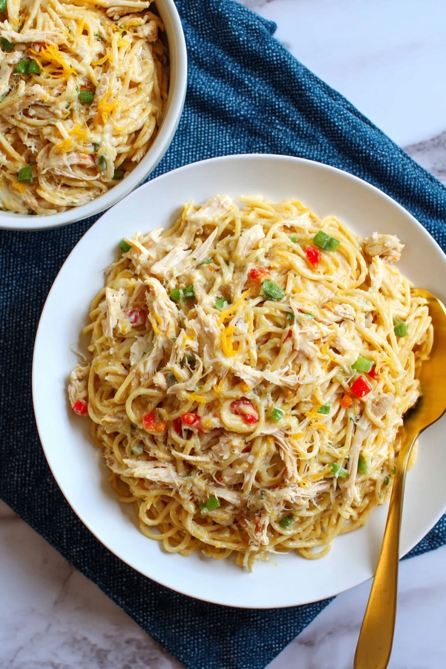 A close-up of a white ceramic baking dish filled with a creamy pasta bake, showing thin spaghetti mixed with melted yellow-orange cheese scattered throughout, small bits of red and green bell peppers, and pieces of white chicken. The top layer is a mix of melted cheese and pasta with a soft and stretchy texture. A spoon is scooping a portion from the bottom right corner, revealing a dense layer of pasta and chicken beneath the surface. Part of the dish is served on a white rectangular plate next to the baking dish. The scene is set on a white marbled surface. photo taken with an iphone --ar 2:3 --v 7 - Southern Chicken Spaghetti Bake, Southern chicken casserole, cheesy chicken pasta bake, hearty Southern comfort food, easy chicken spaghetti recipe