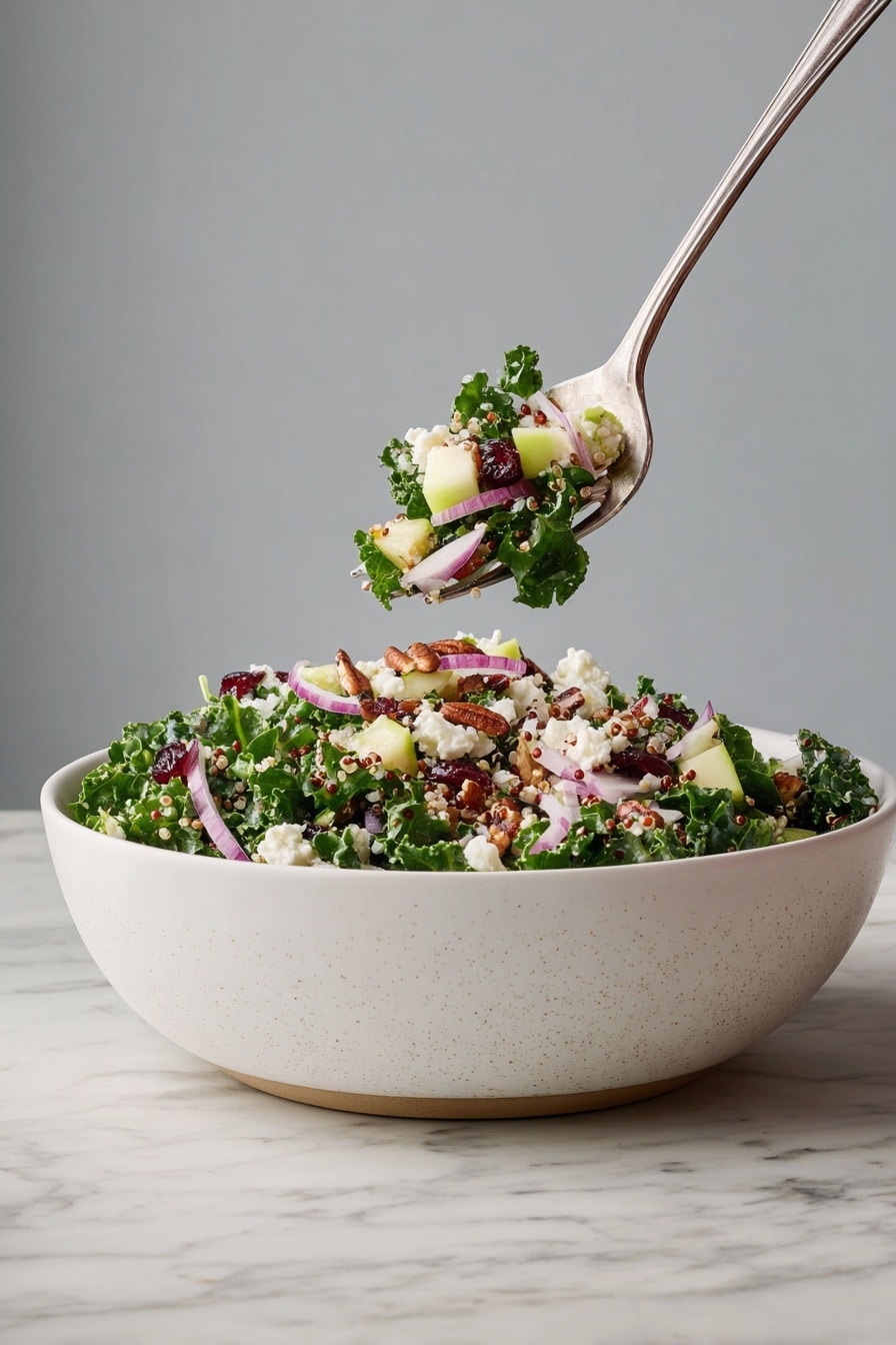A large white bowl filled with layered salad consisting of dark green curly kale leaves, light green apple chunks, small white crumbled cheese pieces, thin slices of purple-red onion, small dark red dried berries, and scattered light brown nuts, all mixed with light-colored quinoa grains. A fork holds one bite of the salad above the bowl, showing the same ingredients. The bowl is placed on a white marbled surface, with a simple gray background. photo taken with an iphone --ar 2:3 --v 7 - Cranberry Apple Quinoa Salad, healthy quinoa salad with cranberries and apples, vegan cranberry apple salad, colorful fruit quinoa salad, nutritious side dish with quinoa and kale