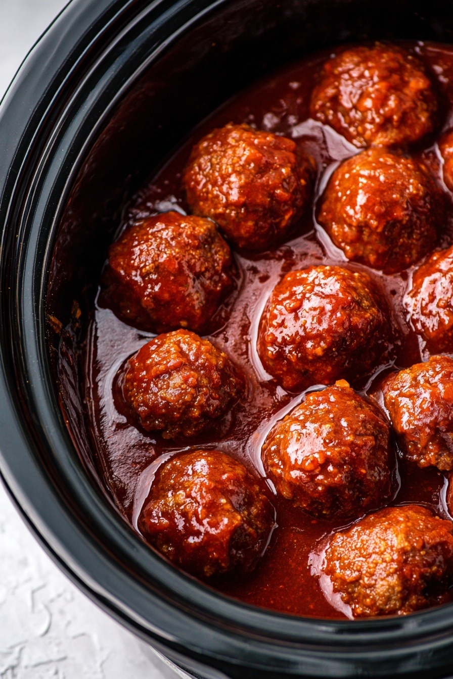 A white round plate filled with about two layers of large meatballs covered in shiny reddish-brown sauce. The plate is slightly tipped, showing meatballs piled high with some sauce pooling at the bottom. A woman's hand with dark red nail polish holds a toothpick picking up the top meatball. The background is a white marbled texture. Photo taken with an iphone --ar 2:3 --v 7 - Slow-Cooker Grape Jelly Meatballs, party appetizer with grape jelly and meatballs, easy slow cooker meatballs recipe, sweet and tangy meatball appetizer, crowd-pleasing party meatballs