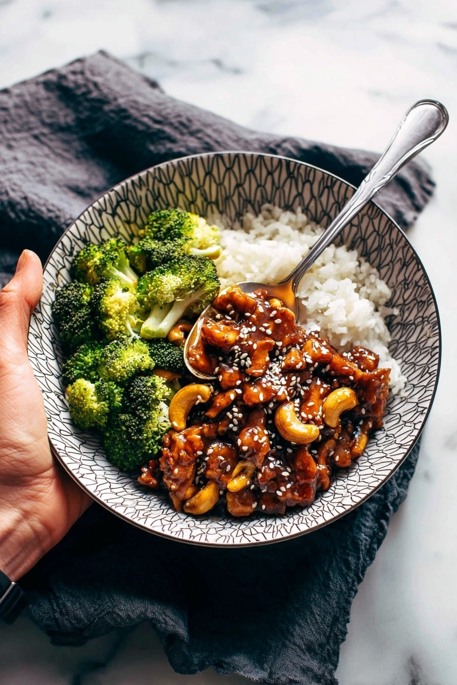 A white bowl with a geometric pattern shows three layers of food: the bottom layer is white rice with a soft, grainy texture, filling about half of the bowl; on one side, bright green broccoli florets with a fresh, bumpy surface are placed next to the rice; covering most of the rice is a thick layer of glossy dark brown chicken pieces mixed with light brown cashew nuts, topped with white sesame seeds. A woman's hand holds a silver spoon, scooping up some rice and chicken from the bowl. The bowl sits on a dark cloth on top of a white marbled surface. photo taken with an iphone --ar 2:3 --v 7 - Cashew Chicken Stir-Fry, easy chicken stir-fry, quick dinner recipes, healthy Asian stir-fry, flavorful chicken and cashews