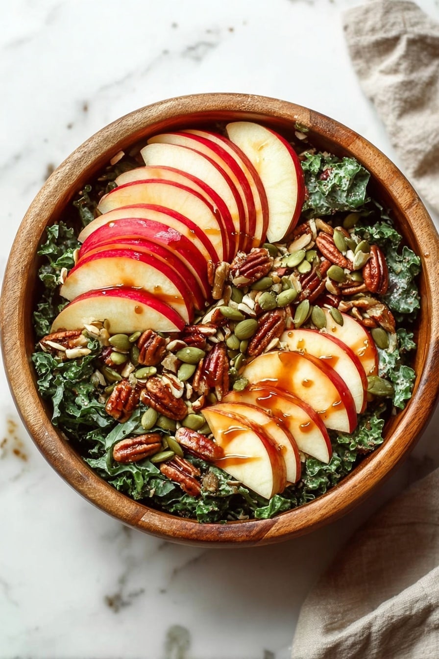 The image shows a fresh salad on a white plate with a thin black rim, placed on a white marbled surface. The salad has several layers: the base is dark green kale leaves with a rough texture, mixed with thin slices of red apple that show white flesh and red skin edges, placed mostly on the top. Scattered over the salad are glossy brown walnuts and green pumpkin seeds, adding texture and color contrast. A reddish-brown dressing lightly coats the salad, giving it a shiny and slightly wet look. There is a gold fork resting on the right side of the plate. The background is softly blurred but has two red apples visible, sitting on the same white marbled surface with a white cloth nearby. Photo taken with an iphone --ar 2:3 --v 7 - Nutty Harvest Honeycrisp Kale Salad, fall kale salad with honeycrisp apples, healthy honeycrisp kale salad recipe, crunchy kale salad with cinnamon vinaigrette, apple and kale salad with nuts
