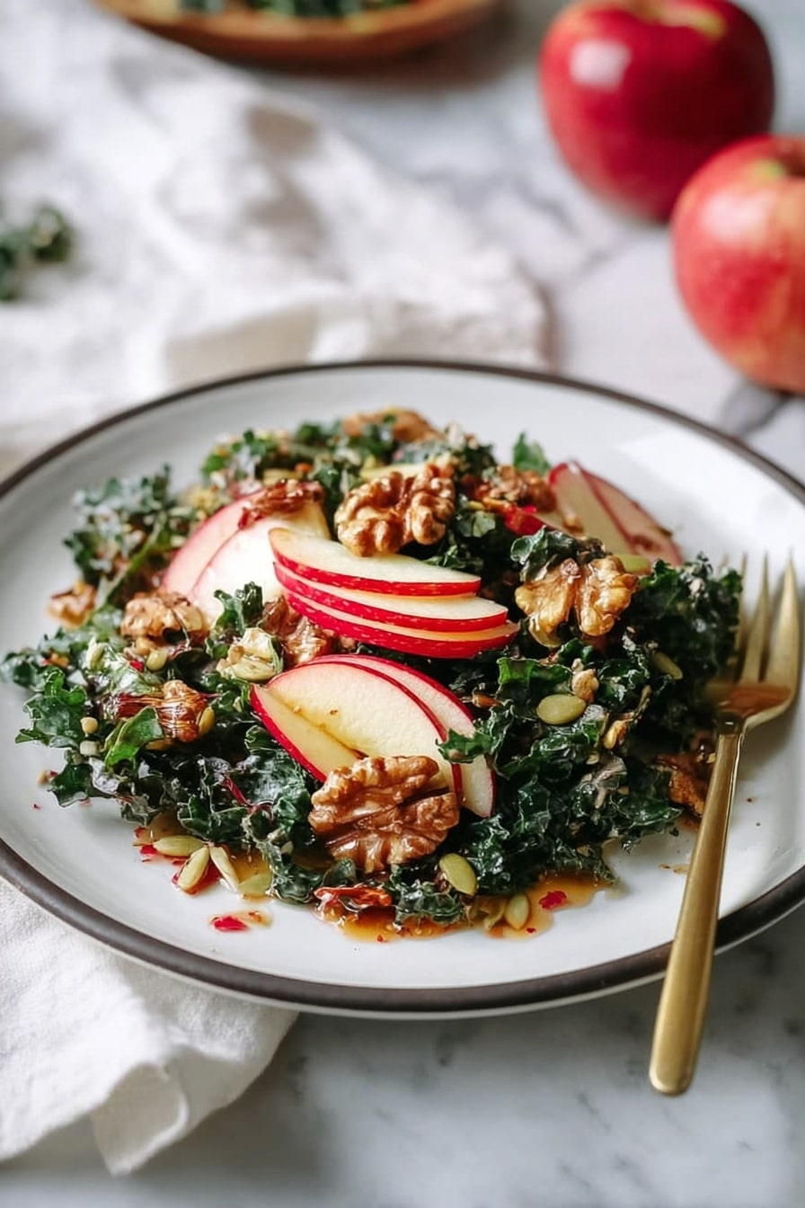 A white plate holds a fresh salad with three main layers. The bottom layer is made of dark green kale leaves with a slightly rough texture. On top of that, there are thin slices of red and white apple arranged evenly, adding a crisp and colorful look. The top layer consists of toasted pecans and green pumpkin seeds scattered over the salad, giving a crunchy texture. The whole dish is lightly coated in a shiny dressing that looks brownish with visible herbs or spices. A gold fork rests on the right side of the plate. The plate is set on a soft white cloth with a white marbled background, accompanied by slices of brown bread and a small glass bowl of dressing nearby. Photo taken with an iphone --ar 2:3 --v 7 - Nutty Harvest Honeycrisp Kale Salad, fall kale salad with honeycrisp apples, healthy honeycrisp kale salad recipe, crunchy kale salad with cinnamon vinaigrette, apple and kale salad with nuts