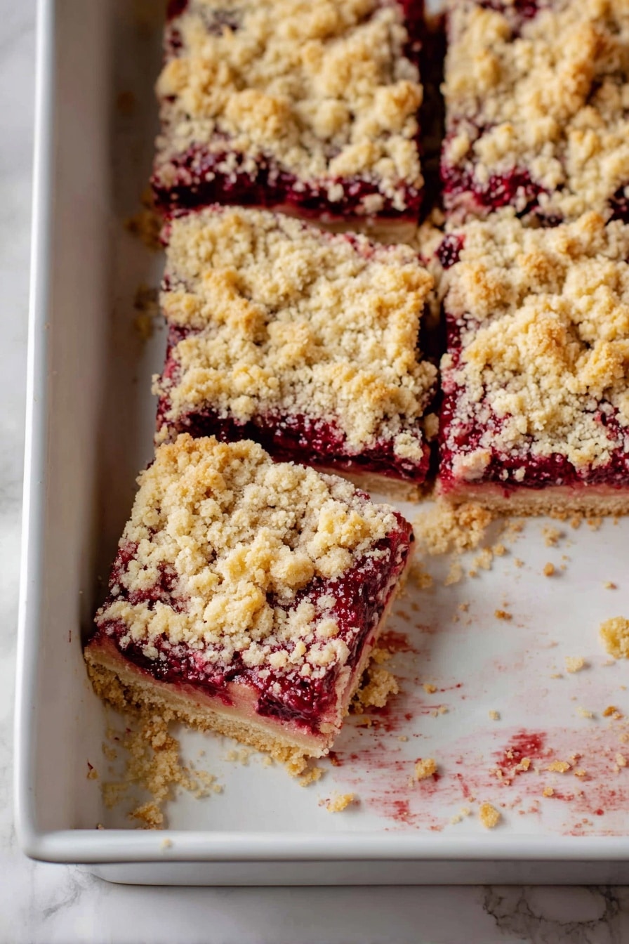 The image shows square pieces of berry crumble bars in a white baking dish with a white marbled surface underneath. Each bar has three layers: a crumbly, golden-yellow topping with a coarse texture, a thick, dark red berry filling that looks juicy and slightly sticky, and a pale, soft base layer holding everything together. One piece is pulled slightly out from the others, revealing crumbs and bits left behind in the dish. The edges inside the dish show some browned spots where the crumble baked more. Photo taken with an iphone --ar 2:3 --v 7 - Cranberry Cobbler Bars, cranberry dessert bars, holiday cranberry bars, easy cranberry cobbler, festive fruit bars