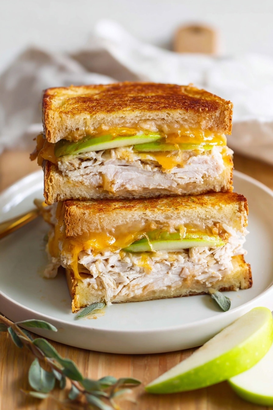 The image shows a tall sandwich cut in half and stacked, placed on a wooden board with a white marbled background. The sandwich has three layers of toasted golden brown bread with a slightly crisp texture. Between the bread layers, there are thick slices of white turkey meat, thin slices of green apple, and melted yellow cheese with a creamy texture, visible melting over and around the meat. The sandwich looks juicy and fresh, with the green apple slices adding a crisp contrast to the soft turkey and cheese. Photo taken with an iphone --ar 2:3 --v 7 - Apple Grilled Cheese with Turkey, savory turkey grilled cheese, apple and cheese sandwich, quick lunch recipes, easy gourmet sandwiches
