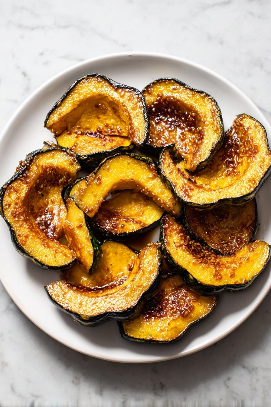 The image shows a white plate filled with about twelve slices of roasted acorn squash, arranged closely together. Each slice has a dark green outer skin and a bright orange, soft inside that looks caramelized and slightly shiny with a golden-brown glaze. Some pieces have a bit of salt sprinkled on top, adding texture. A silver spoon rests on the side of the plate. The plate is placed on a white marbled surface. photo taken with an iphone --ar 2:3 --v 7 - Roasted Acorn Squash with Chili Powder Cumin Brown Sugar, cozy fall side dish, roasted acorn squash recipe, sweet and spicy roasted squash, healthy winter side