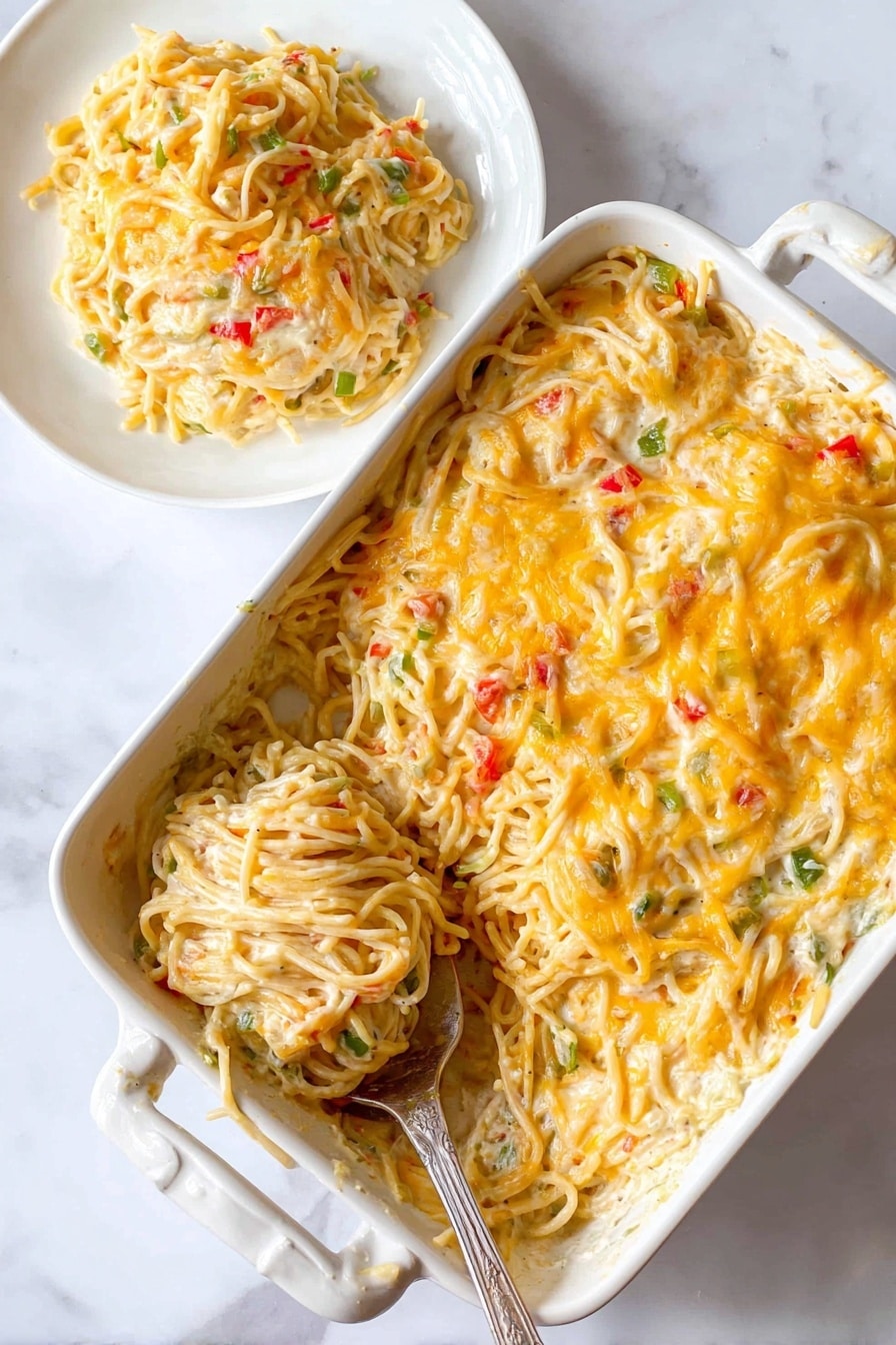 The image shows a close-up of a large white plate filled with creamy spaghetti mixed with shredded chicken pieces and small bits of green and red bell peppers. The pasta is coated in a light yellowish creamy sauce with some cheese sprinkled on top, creating a soft texture with scattered bright colors. A golden spoon is partially visible on the right side of the plate. In the background, there is another white bowl with a similar dish, placed on a folded dark blue cloth on a wooden surface, all set against a white marbled texture. Photo taken with an iphone --ar 2:3 --v 7 - Southern Chicken Spaghetti Bake, Southern chicken casserole, cheesy chicken pasta bake, hearty Southern comfort food, easy chicken spaghetti recipe