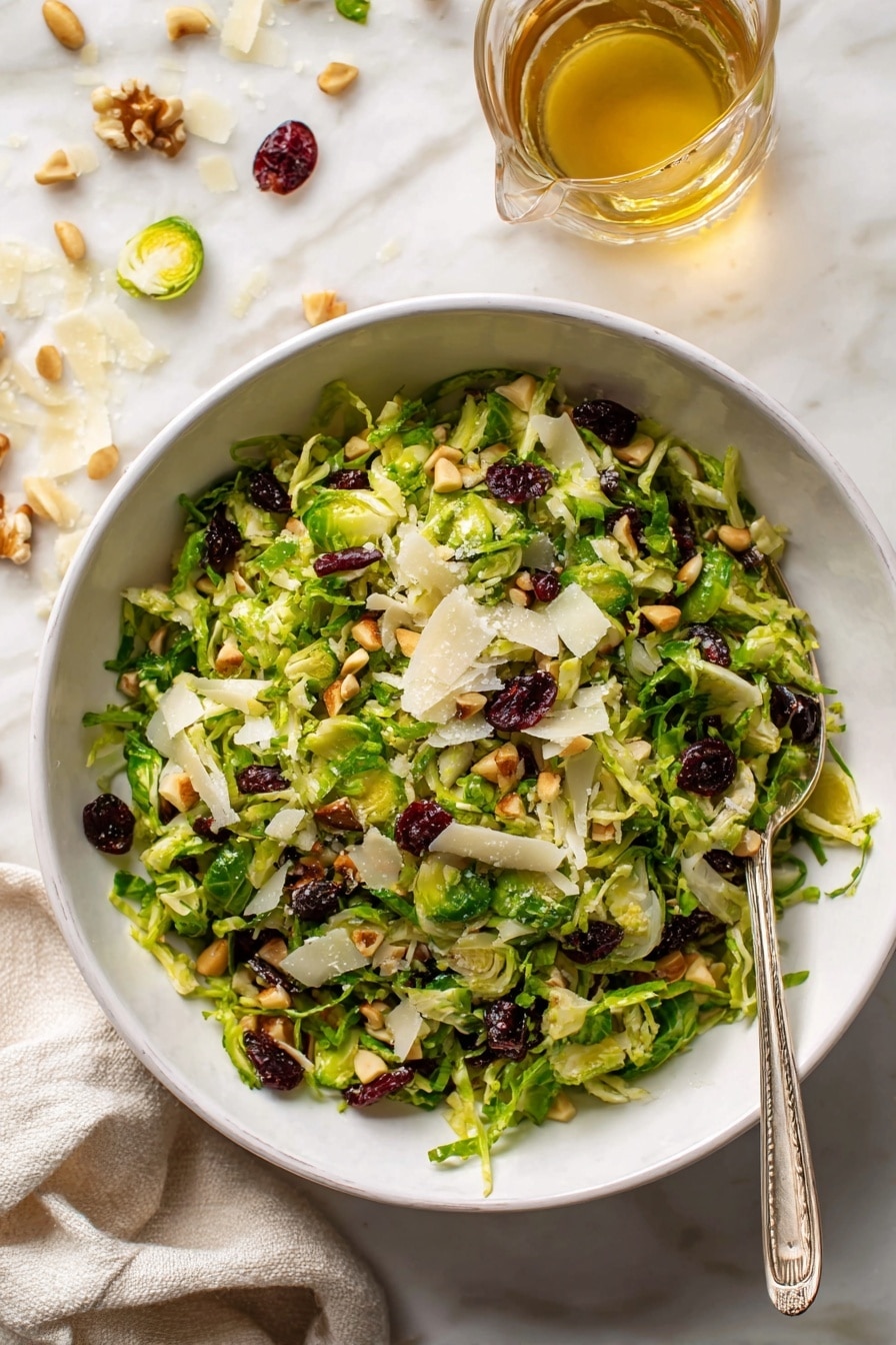A white bowl filled with a fresh salad that has three main layers: the bottom layer is thinly sliced bright green Brussels sprouts, the middle layer is scattered dark red dried cranberries, and the top layer has small toasted pine nuts and white, thin shavings of cheese spread evenly over the salad. To the right side of the bowl, there is a small clear glass bowl with a yellow dressing and a spoon inside. The whole scene is set on a white marbled surface with some cheese shavings and pine nuts scattered around. Photo taken with an iphone --ar 2:3 --v 7 - Brussels Salad with Spiced Maple Vinaigrette, Brussels sprout salad, Maple vinaigrette salad, healthy Brussels sprout dish, easy Brussels salad recipe