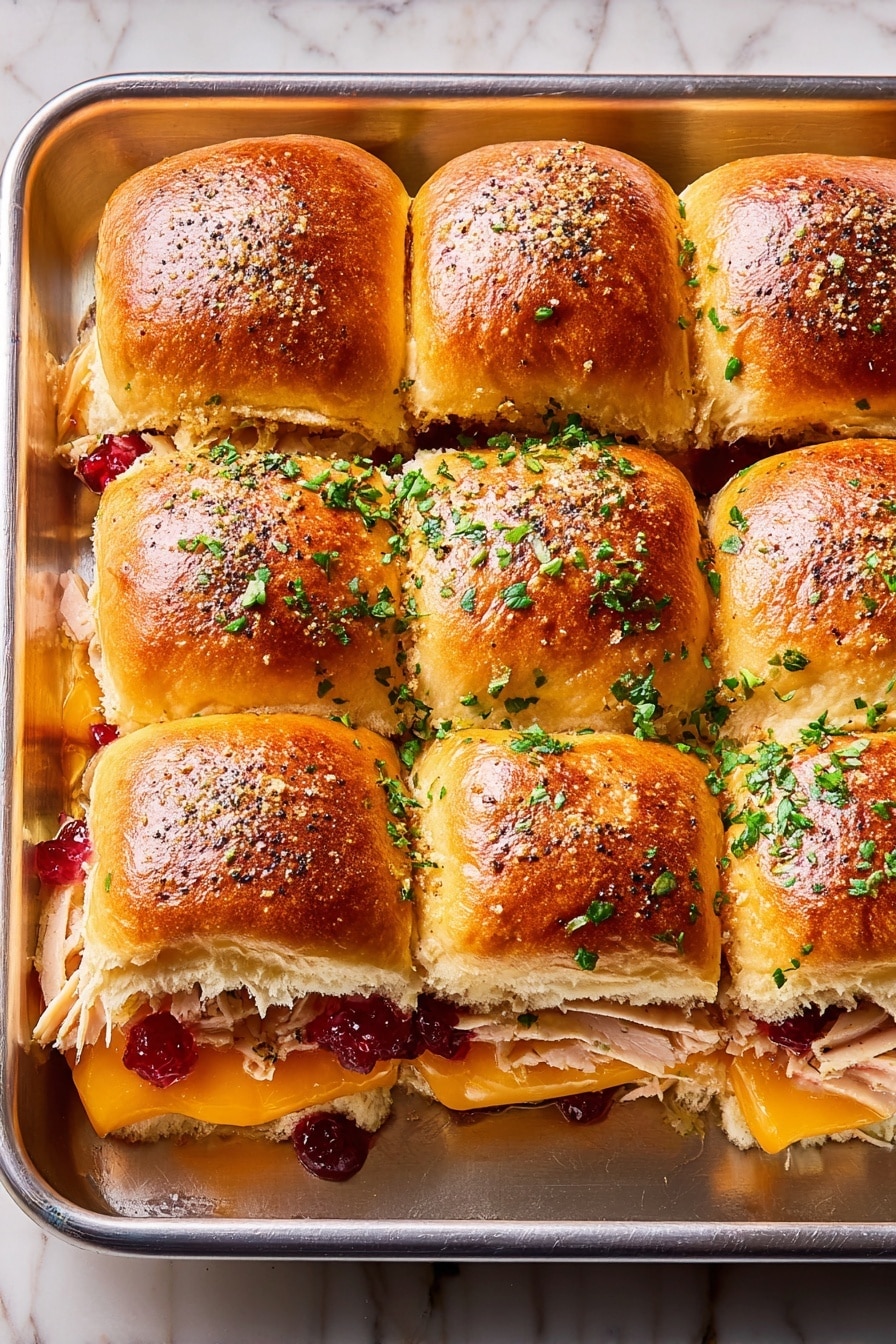 The image shows a tray with nine soft, golden-brown slider buns arranged in a 3x3 grid. Each bun has a shiny, slightly toasted top sprinkled with chopped green herbs and black pepper seeds. Inside the sliders, layers of light cooked chicken sit below bright orange melted cheese, with red cranberry sauce peeking out around the edges. On the right side, a woman's hand is lifting one slider, revealing gooey, stretchy cheese strands between the buns. The tray rests on a white marbled surface. Photo taken with an iphone --ar 2:3 --v 7 - Cranberry Turkey Sliders, Thanksgiving sliders, holiday party appetizers, easy turkey sliders, cranberry chicken sliders