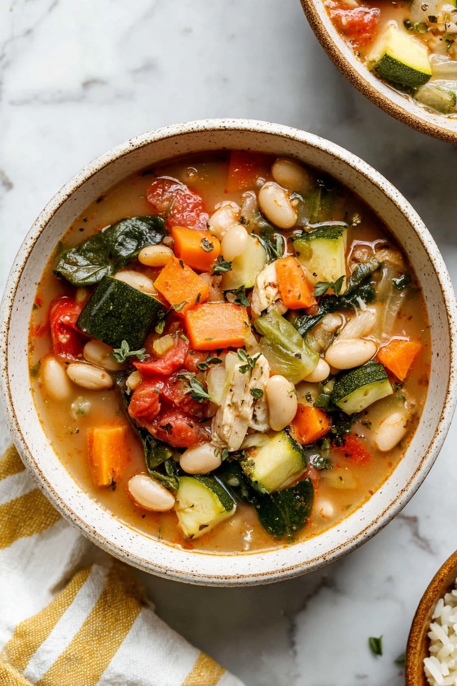 A close-up of a bowl filled with colorful vegetable soup on a white marbled surface. The soup has many layers of ingredients: bright orange carrot slices, green zucchini chunks, green spinach leaves, red tomato pieces, pale white beans, and light beige small pieces of a soft ingredient, all floating in a light brown broth speckled with black pepper and herbs. A silver spoon sits inside the bowl, holding a mix of zucchini, beans, and tomato. The bowl itself is off-white with a light brown rim. photo taken with an iphone --ar 2:3 --v 7 - Tuscan Chicken Vegetable Stew, Tuscan Chicken Stew, hearty chicken vegetable stew, Italian chicken stew, healthy chicken vegetable soup