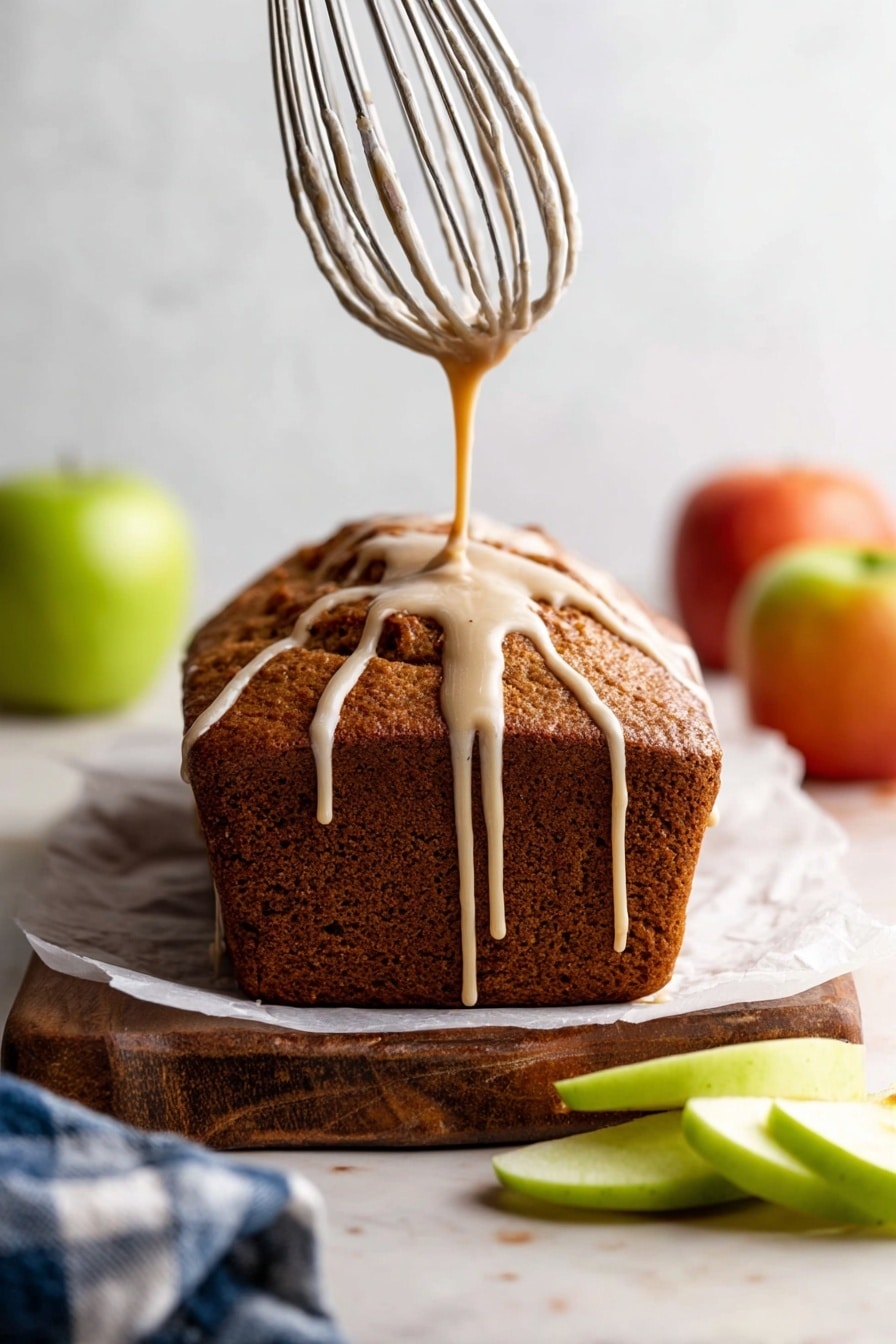 The image shows four thick slices of apple cinnamon bread lined up on a piece of white parchment paper on a wooden board. Each slice has a golden-brown crust and a soft, textured inside filled with chunks of white apple pieces. Three cinnamon sticks lie next to the bread on the left side. On the right, there are several thin green apple slices neatly stacked. A striped blue and white cloth is partially visible in the upper background next to a red and yellow apple. The scene is on a white marbled surface. Photo taken with an iphone --ar 2:3 --v 7 - Apple Bread with Cider Glaze, apple bread recipe, spiced apple bread, fall apple bread, apple loaf with cider glaze