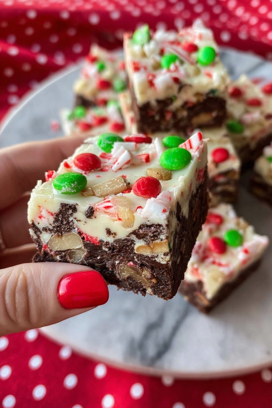 The image shows a glass square dish filled with multiple square pieces of a two-layered dessert. The bottom layer is dark brown with a dense, fudgy texture, while the top layer is creamy white. The white layer is decorated with red and green candy-coated chocolates scattered on top along with small pieces of crushed peppermint candies that add red, white, and green colors. The dish sits on a white marbled surface. photo taken with an iphone --ar 2:3 --v 7 - Christmas Peppermint Slice, festive peppermint chocolate slice, holiday no-bake dessert, easy Christmas treats, peppermint holiday sweets