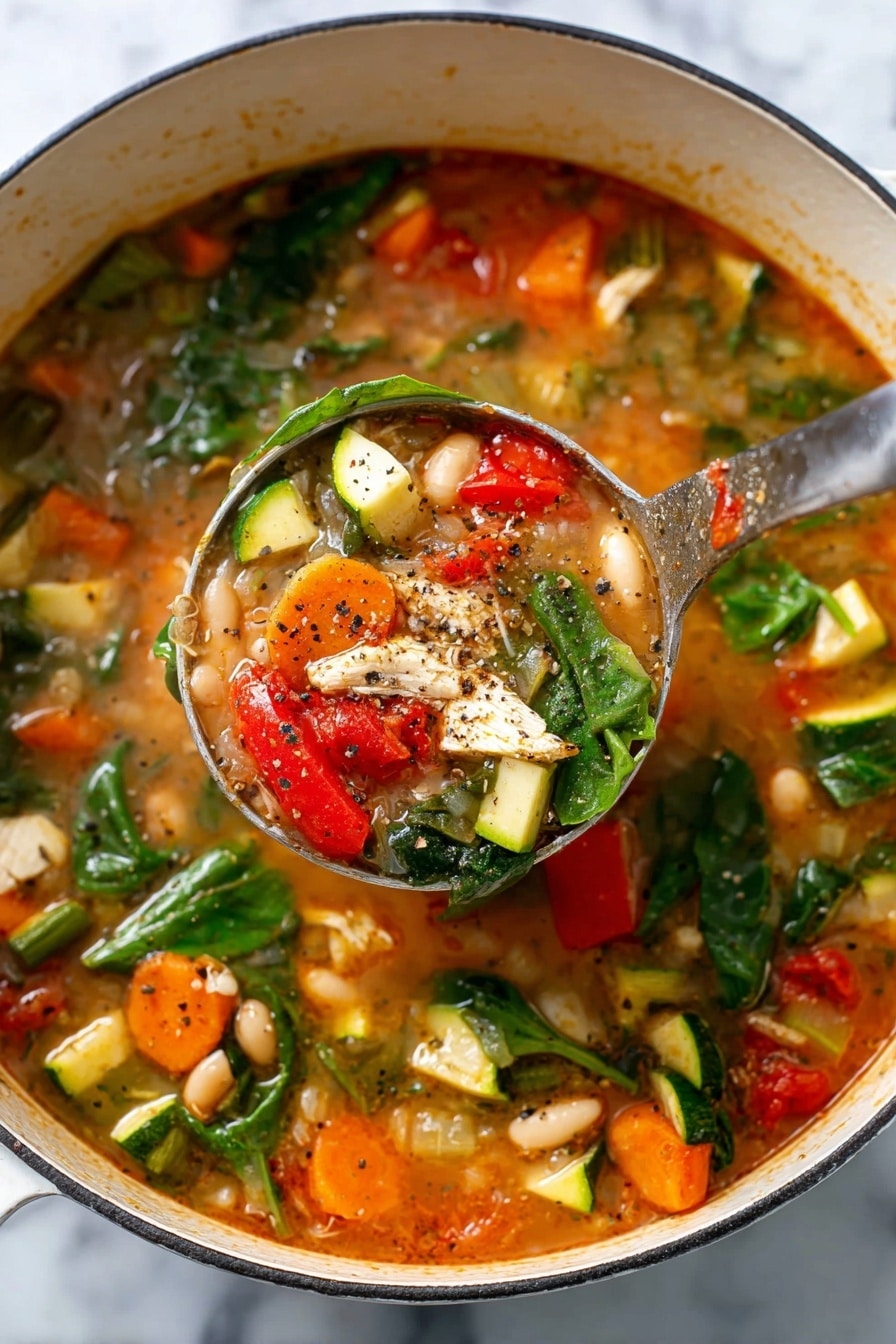 A close-up view of a bowl filled with chunky vegetable soup that has about three layers visible: the bottom layer is a light brown broth, the middle layer is a mix of white beans and diced orange carrots scattered around, and the top layer shows pieces of green zucchini, red tomatoes, celery, dark green spinach leaves, and small white pieces of chicken, all sprinkled with herbs. The bowl is round and white with a natural speckled rim, placed on a white marbled surface next to a white cloth with yellow stripes, and a small part of another bowl with rice is visible at the top right corner. photo taken with an iphone --ar 2:3 --v 7 - Tuscan Chicken Vegetable Stew, Tuscan Chicken Stew, hearty chicken vegetable stew, Italian chicken stew, healthy chicken vegetable soup