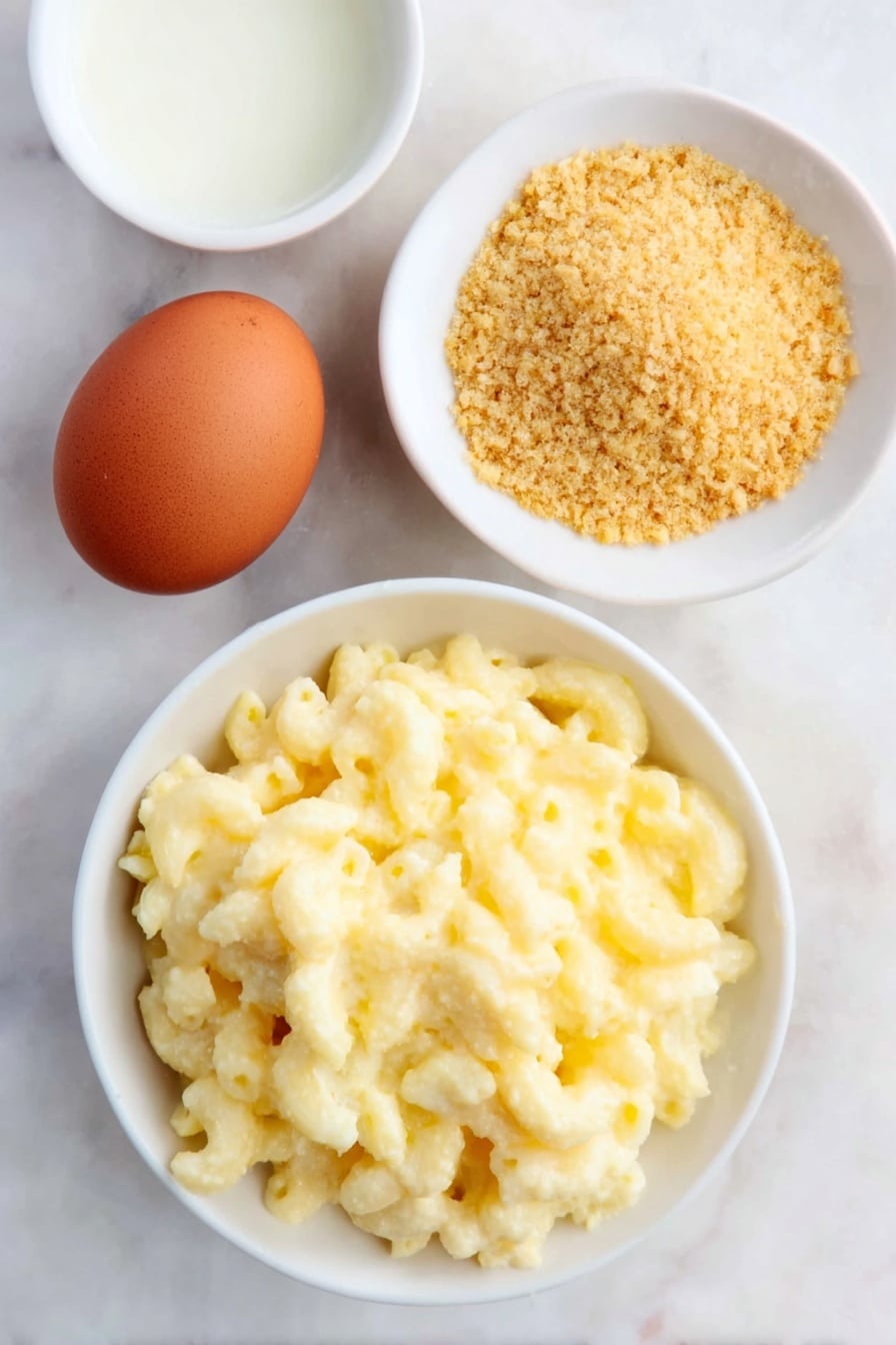 Flat lay of a small pile of creamy macaroni and cheese made with elbow macaroni, one whole large brown egg with a clean shell, a small white ceramic bowl filled with golden panko breadcrumbs, and a small white ceramic bowl with clear golden vegetable oil, all arranged symmetrically in realistic proportions on a clean white marble surface, soft natural light, photo taken with an iPhone, professional food photography style, fresh ingredients, white ceramic bowls, no bottles, no duplicates, no utensils, no packaging --ar 2:3 --v 7 --p m7354615311229779997 - Crispy Fried Mac and Cheese Balls, cheesy appetizer, crunchy cheese bites, easy snack recipes, comfort food snacks