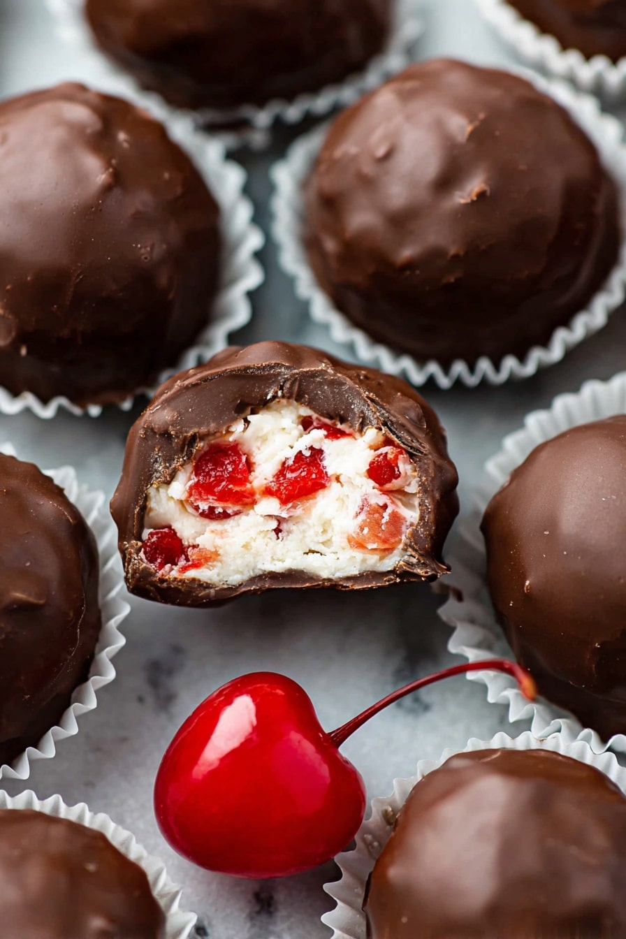 The image shows a group of round chocolate-covered balls arranged closely on white marbled texture. Each ball has a smooth, shiny, dark brown chocolate coating with a slightly bumpy surface. Two of the balls are bitten to show a creamy white filling layered with small red fruit pieces inside. There are two bright red cherries with stems placed near the chocolate balls, adding a bright color contrast. A peach-colored cloth is partly visible on the bottom left corner, giving a soft texture to the setting. The photo was taken with an iphone --ar 2:3 --v 7 - Martha Washington Cherry Balls, holiday cherry candies, nostalgic holiday treats, festive coconut pecan candies, cherry truffles with chocolate coating
