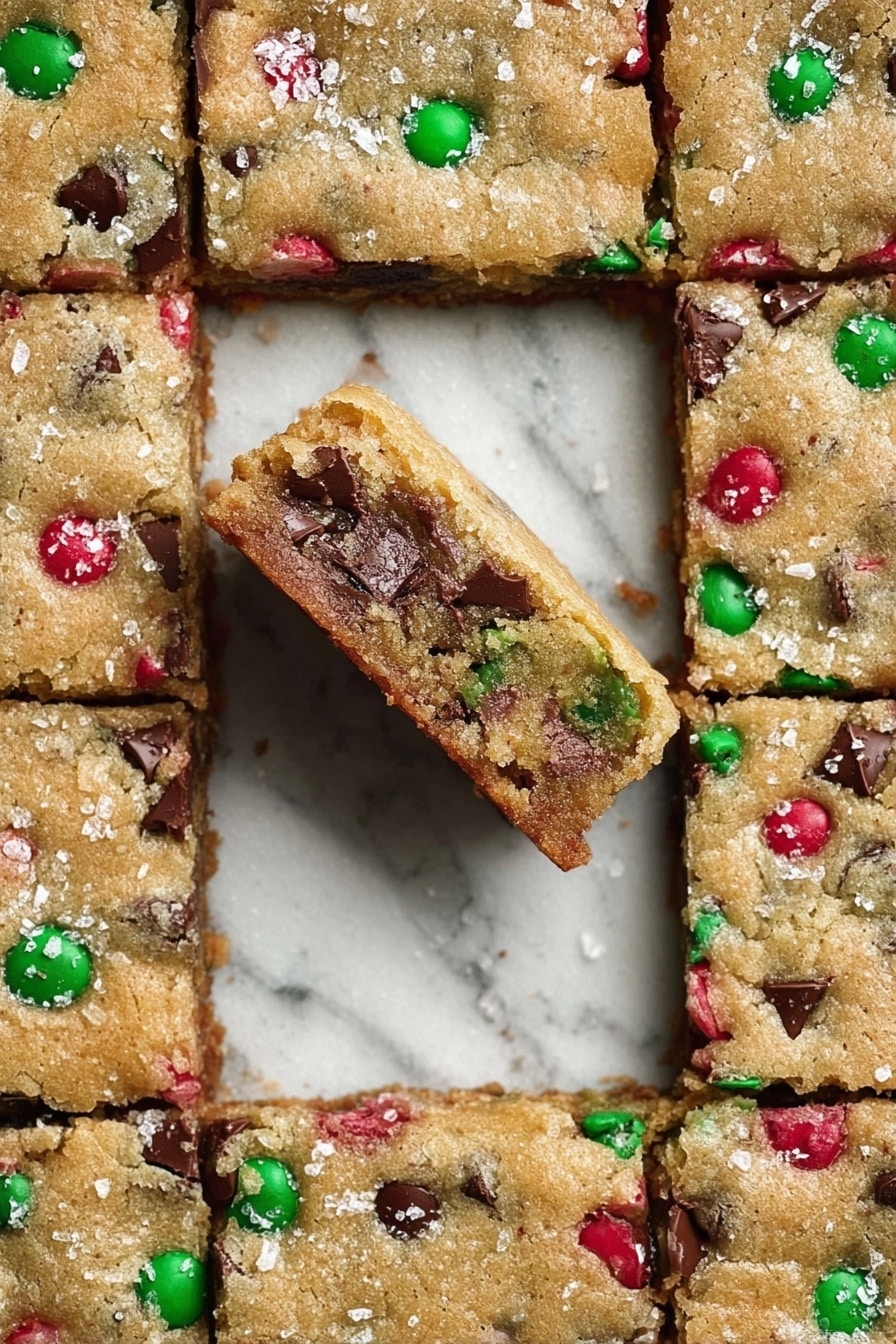 There is a stack of four square cookie bars placed on white crinkled paper over a white marbled surface. Each bar is golden brown with a soft, slightly crumbly texture and is filled with melted dark chocolate chunks and scattered red and green candy pieces resembling M&M’s. A few green and red candy pieces are lying around the stack on the white marbled surface. The cookie bars have an inviting, homemade look, with slightly uneven edges and a hint of glossy chocolate melting on the sides. photo taken with an iphone --ar 2:3 --v 7 - Chewy Browned Butter Blondies, Browned Butter Blondies recipe, easy blondies with browned butter, chewy blondie bars, festive blondie dessert