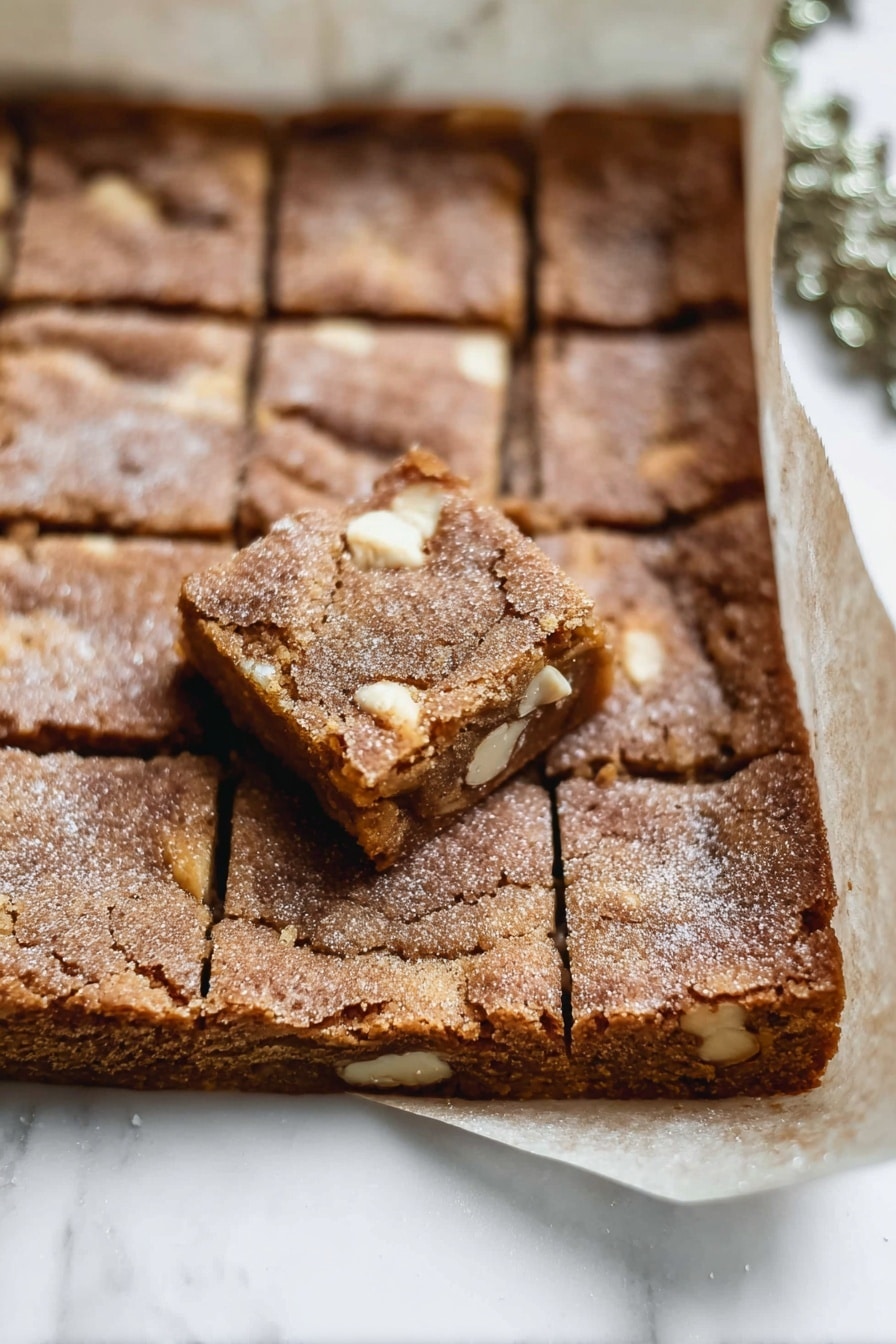 The image shows a stack of four square blondies, each with a golden brown color and small white chips inside. The blondies have a soft and crumbly texture with some sugar crystals visible on top. The bottom blondie is larger and the stack narrows slightly at the top. Around the stack, a few white chips lie on a white marbled surface, which adds a clean and simple background to the treat. Photo taken with an iphone --ar 2:3 --v 7 - Gingerbread Blondies with White Chocolate, gingerbread blondies, white chocolate blondies, holiday blondie recipe, spiced dessert blondies