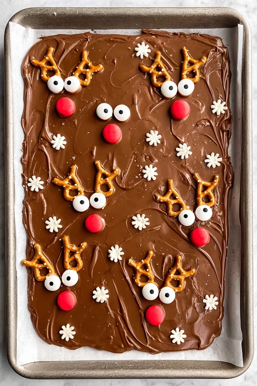 A large rectangle layer of smooth, milk chocolate is spread unevenly on white baking paper over a metal tray. On top, there are several reindeer faces made from small pretzel loops for antlers, white candy eyes with black dots, and round red candies for noses. Scattered around the reindeer are small white round and flower-shaped sprinkles. The chocolate layer is light brown and glossy with soft swirl marks. photo taken with an iphone --ar 2:3 --v 7 - Reindeer Chocolate Bark with Pretzels, holiday chocolate bark, festive Christmas treats, easy holiday snacks, reindeer dessert ideas