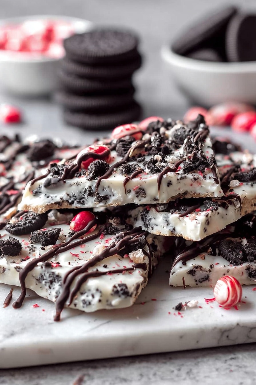 The image shows several pieces of white chocolate bark stacked unevenly on a white marbled surface. The bark has a creamy white base with embedded small dark cookie bits, giving a speckled black-and-white look. On top, there are drizzles of dark chocolate in thin, wavy lines. Scattered across the bark are crushed red candy pieces and cookie crumbs, adding splashes of red and black to the white base. In the background, there are whole dark cookies and a white bowl with more crushed red candy, slightly out of focus. The texture looks smooth on the white base with rough cookie pieces and crunchy candy on top. photo taken with an iphone --ar 2:3 --v 7 - Oreo Peppermint Bark, peppermint bark recipe, holiday dessert, peppermint chocolate bark, quick Christmas treats