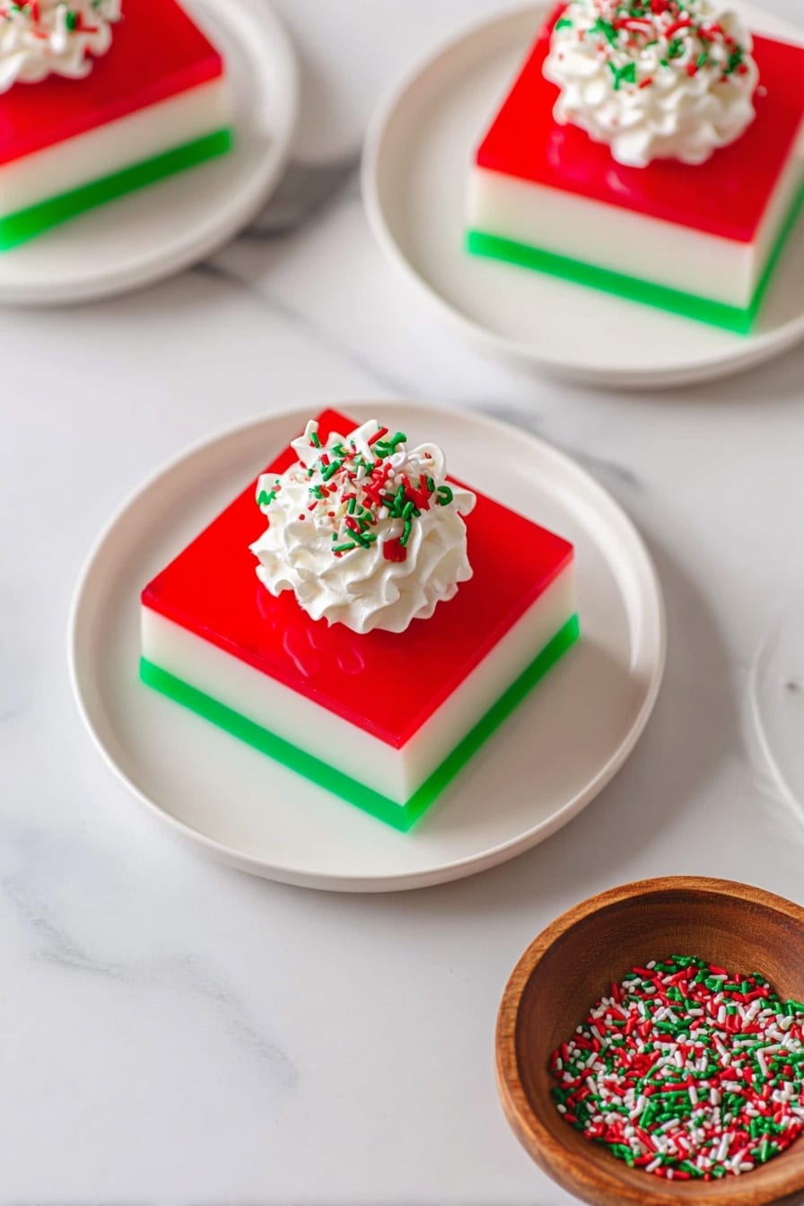This image shows a slice of layered gelatin dessert on a white plate with three visible layers: the bottom layer is bright green and clear, the middle layer is creamy white and opaque, and the top layer is translucent red. The dessert is topped with a dollop of white whipped cream sprinkled with red and green sprinkles. A silver fork is lifting a square piece of the dessert from the plate, holding it above the main slice. The background has a white marbled texture with festive decorations including pine cones, red berries, green leaves, and a woven basket, adding a holiday feel. Photo taken with an iphone --ar 2:3 --v 7 - Christmas Ribbon Salad, festive layered Jell-O salad, holiday side dish, colorful party salad, Christmas dessert salad