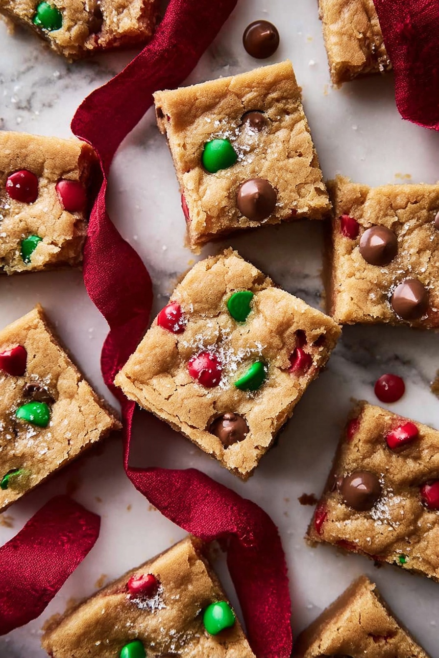 The image shows several square cookie bars arranged on a white marbled surface. Each cookie bar has a golden-brown top layer that looks soft and slightly crumbly, with small red and green candy pieces embedded throughout. On top of many cookie bars, there is a dollop of melted chocolate, some with a small pinch of coarse salt sprinkled over. One cookie bar is stacked on another, and it has a bite taken out of it, showing the chocolate melting inside. A deep red velvet cloth is placed among the cookie bars, adding a touch of rich color contrast. photo taken with an iphone --ar 2:3 --v 7 - Brown Butter M&M Cookie Bars, chocolate chip cookie bars, festive cookie bar recipe, chewy M&M bars, easy cookie bar dessert